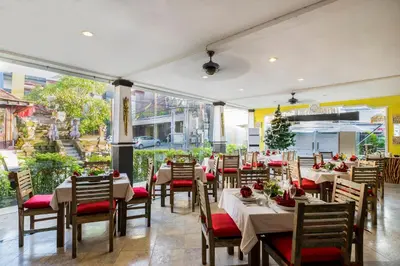 a restaurant with tables and chairs and a large window at Royal Hotel and Villa Bali in Legian