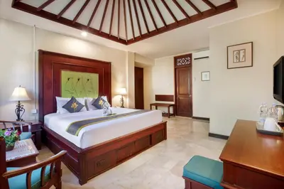 a bedroom with a bed and a desk and a television at Royal Hotel and Villa Bali in Legian