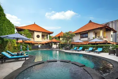 a swimming pool with chairs and umbrellas in front of a house at Royal Hotel and Villa Bali in Legian