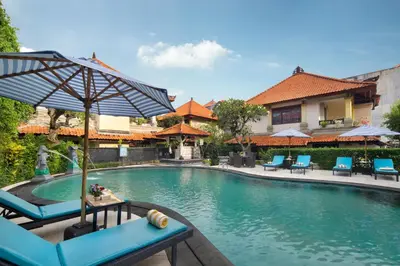 a pool at a resort with chairs and an umbrella at Royal Hotel and Villa Bali in Legian