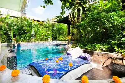 a pool with a bed next to a swimming pool at Villa Besok in Seminyak