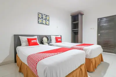 two beds in a room with red and white sheets at Capital O 1666 Grand Pudjawan Hotel Near Kuta Beach in Kuta