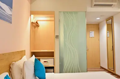 a bedroom with a bed with blue pillows and a closet at The ONE Legian in Legian
