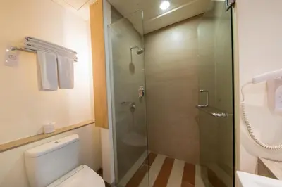 a bathroom with a toilet and a glass shower at The ONE Legian in Legian