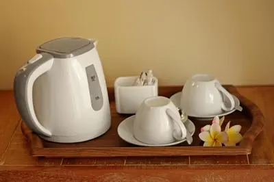 a tea kettle and cups on a wooden tray at Mina Pelasa Hotel in Legian