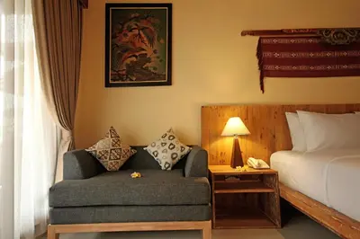 a bedroom with a bed and a couch next to a bed at Mina Pelasa Hotel in Legian