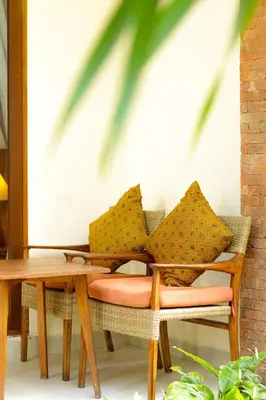 a wooden table and chairs with yellow pillows on it at Mina Pelasa Hotel in Legian