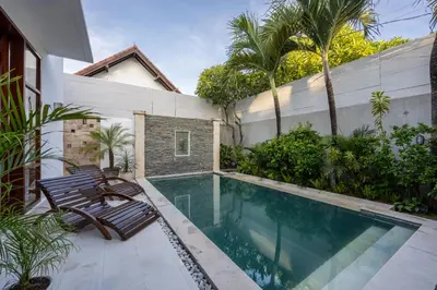 a swimming pool with two chairs next to a house at Villa Manis La Bora in Seminyak in Seminyak