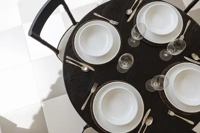 a black table with plates and wine glasses on it at Puri Pani in Seminyak