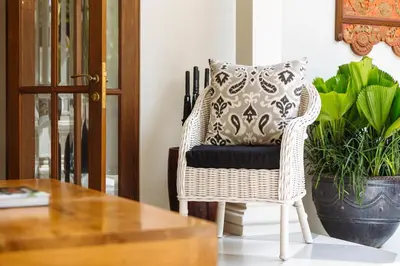 a wicker chair with a pillow on it next to a table at Puri Pani in Seminyak