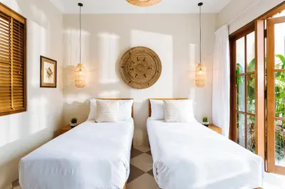 two beds in a room with windows at Puri Pani in Seminyak