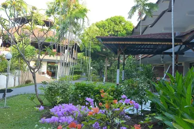 a garden with flowers in front of a building at Palm Beach Hotel Bali in Kuta