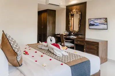 a bedroom with a bed with two swans and a desk at Palm Beach Hotel Bali in Kuta