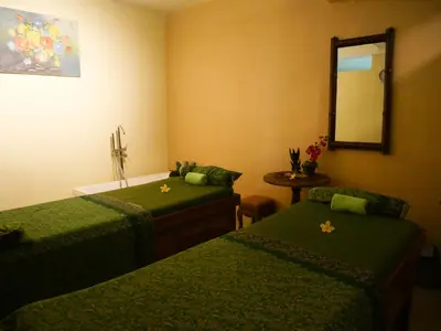 a room with two green beds and a mirror at Palm Beach Hotel Bali in Kuta