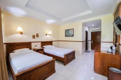 a hotel room with two beds and a television at Palm Beach Hotel Bali in Kuta
