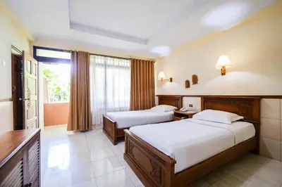 a hotel room with two beds and a window at Palm Beach Hotel Bali in Kuta