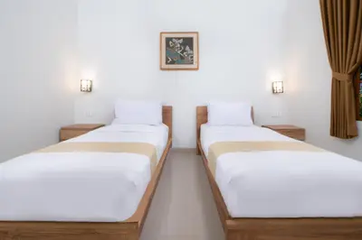 two beds in a room with white walls at Villa Bunga Hotel in Seminyak