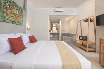 a bedroom with a large white bed and a bathroom at Villa Bunga Hotel in Seminyak