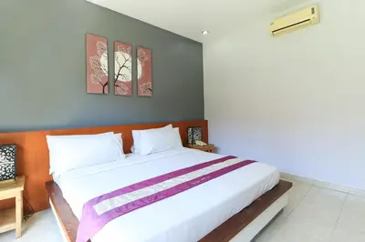 a bedroom with a large white bed with two pictures on the wall at Bali Merita Villa in Canggu