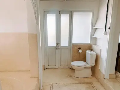 a bathroom with a toilet in front of a door at Kresna By The Sea By Kresna Hospitality in Seminyak