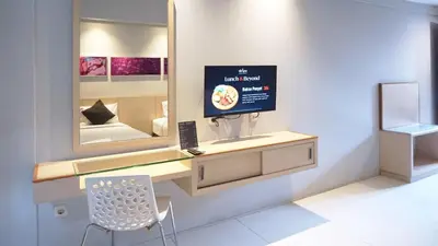a room with a vanity with a tv and a mirror at Conjioo Hotel Kuta Managed By MHM in Legian