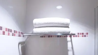 a stack of towels on a shelf in a bathroom at Conjioo Hotel Kuta Managed By MHM in Legian