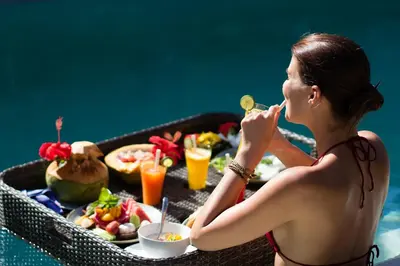 a woman eating food next to a tray of food at Chandra Bali Villas in Seminyak