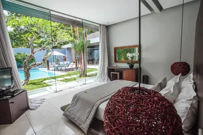 a bedroom with a bed and a large window at Kembali Villas in Seminyak