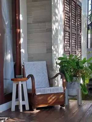a rocking chair on a porch with a plant at Dim House Jimbaran in Jimbaran