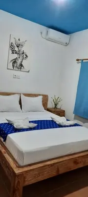 a bedroom with a wooden bed with a drawing on the wall at Turtle Island Homestay in Sanur