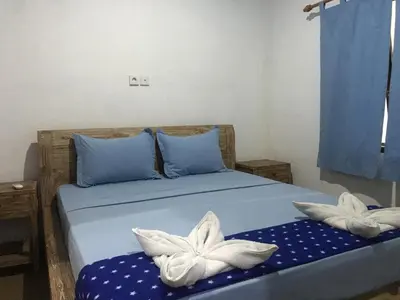 a bedroom with a bed with two white flowers on it at Turtle Island Homestay in Sanur