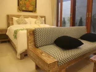a bedroom with a bed and a couch and a window at Green Studio Apartment Seminyak in Seminyak