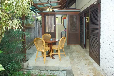 a patio with a table and chairs and a ceiling at Pondok Agung Bed & Breakfast in Nusa Dua