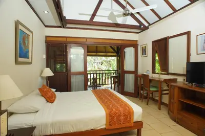 a bedroom with a bed and a desk and a television at Pondok Agung Bed & Breakfast in Nusa Dua