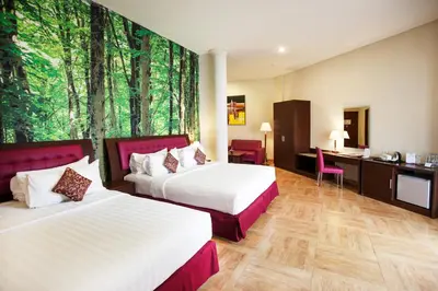 a hotel room with two beds and a desk at Kuta Central Park Hotel in Kuta