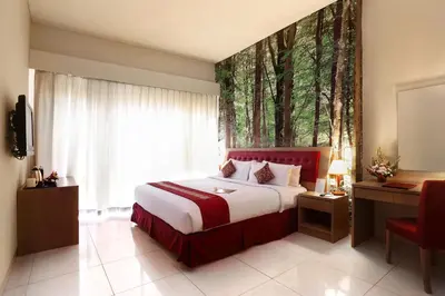 a bedroom with a bed and a window with trees at Kuta Central Park Hotel in Kuta