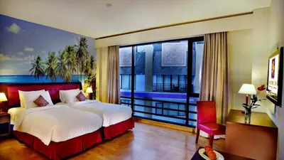 a bedroom with a large bed and a large window at Kuta Central Park Hotel in Kuta