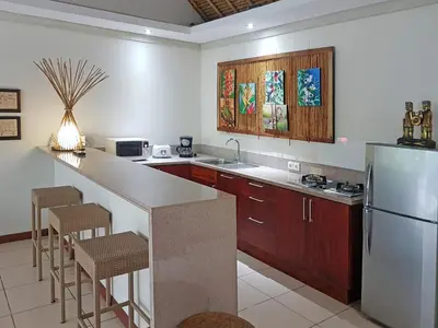 a kitchen with a refrigerator and a counter with stools at Villa Kakariki in Kerobokan