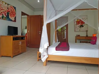 a bedroom with a canopy bed and a television at Villa Kakariki in Kerobokan
