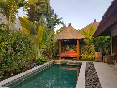 a backyard with a swimming pool and a gazebo at Villa Kakariki in Kerobokan