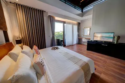 a bedroom with a large bed and a flat screen tv at Mokko Suite Villas Umalas Bali in Seminyak
