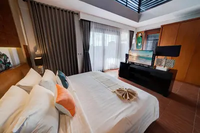 a bedroom with a large bed and a flat screen tv at Mokko Suite Villas Umalas Bali in Seminyak