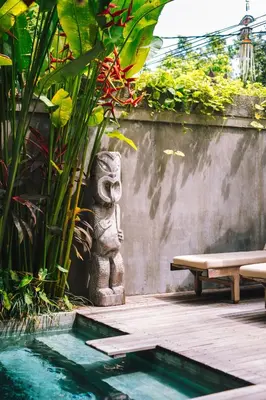 a bench and a statue next to a pool at Villa Vickary Seminyak in Seminyak