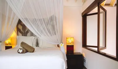 a bedroom with a bed with white curtains and a window at Villa Vickary Seminyak in Seminyak