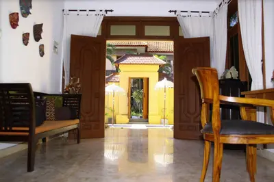 a living room with a yellow door and a table and chairs at Villa Putu Mira By Maha Bali in Kuta