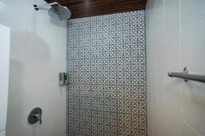 a shower in a bathroom with a tile wall at The Kubu Hotel in Kuta