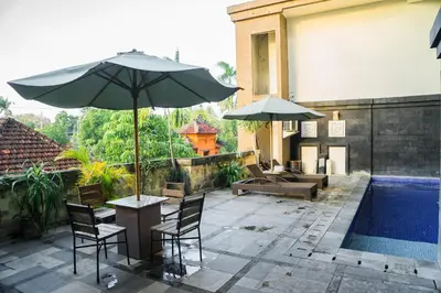 a patio with a table and chairs and an umbrella at Hotel Puri Ayu in Denpasar