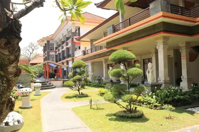 a courtyard of a building with trees and bushes at Grand Sinar Indah in Legian