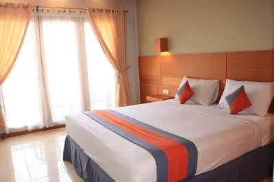 a bedroom with a large bed in a room with windows at Grand Sinar Indah in Legian