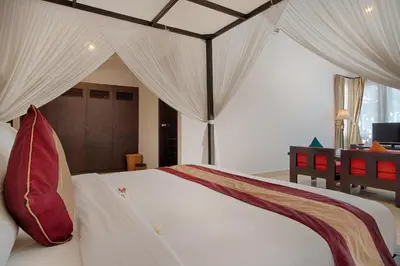 a bedroom with a large white bed with curtains at The Tukad Villa in Seminyak